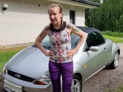 Anni Vuohensilta is standing in front of her car with her hands on her hips.